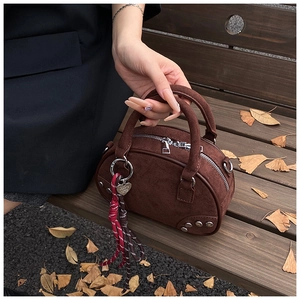 Détail du sac bowling en daim marron foncé avec rivets et breloques de décoration