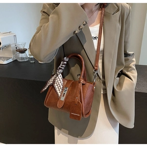 Détail d'un sac seau vintage en cuir marron avec une poignée décorée d'un foulard en soie