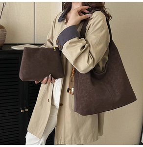 Detail of dark brown vintage tote bag with matching pouch on casual trench coat