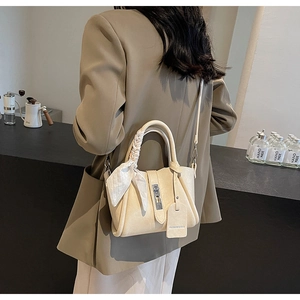 Détail d'un sac seau en cuir beige avec poignée foulard en soie et fermoir métallique