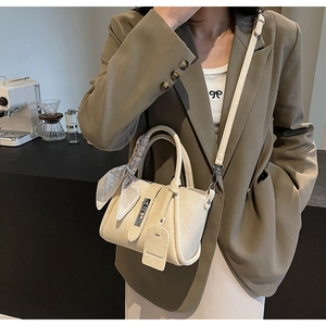 Détail du sac seau crème avec poignée en foulard de soie sur un comptoir de café