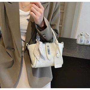 Détail d'un sac seau en cuir beige avec foulard en soie et fermoir rotatif argenté