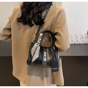 Détail du sac seau en cuir noir avec anse foulard à carreaux et fermoir métallique