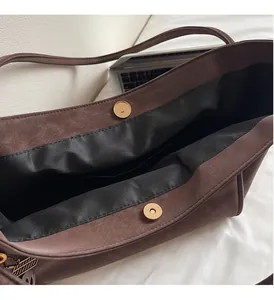 Detail of vintage brown leather tote bag with gold magnetic snaps and black lining