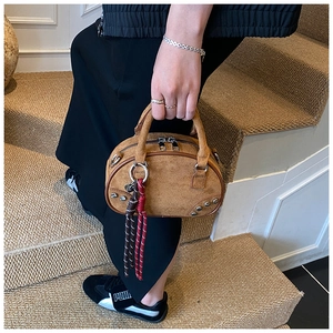 Détail du sac bowling en daim camel avec rivets argentés et charms en corde tressée