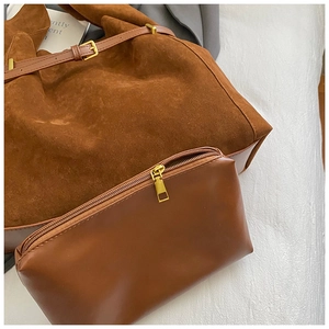 Détail du sac fourre-tout en daim marron caramel et pochette assortie à fermeture