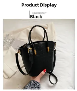 Detailed view of black crocodile pattern leather handbag with gold hardware details