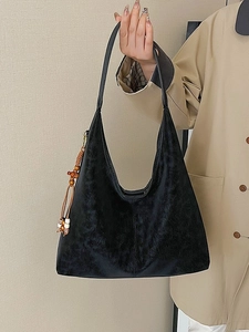 Minimalist black large tote bag with wooden bead tassel shown in street style view