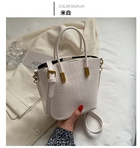 Detailed view of beige faux-crocodile embossed bucket bag with premium gold hardware