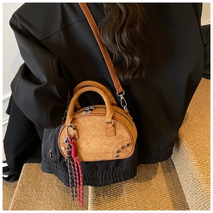 Détail du sac boston en daim beige avec rivets argentés et pendentif en corde tressée
