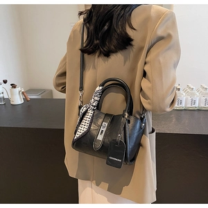 Détail du sac seau noir avec anse en foulard à carreaux et étiquette de mode
