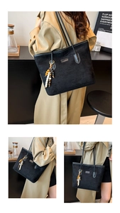 Detail of black suede tote bag featuring multi-color wooden bead tassel and leather straps