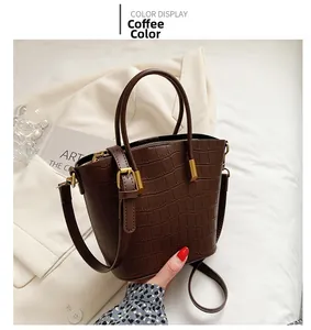 Detail of a brown crocodile texture bucket bag with gold hardware and top handle