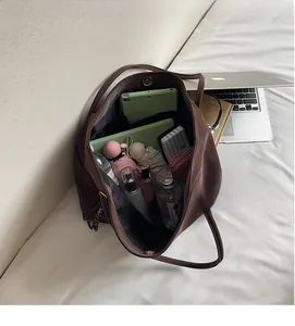 Spacious dark brown tote bag interior filled with everyday items to show storage capacity
