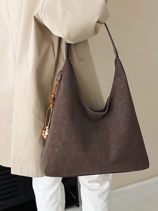 Minimalist large brown leather tote bag with ethnic beaded charm shown on model