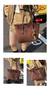Detail of dark brown suede tote bag with stylish wooden bead pendant and slim straps