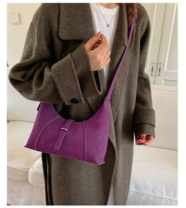 Detail of purple matte leather hobo bag with metal buckle on brown wool coat