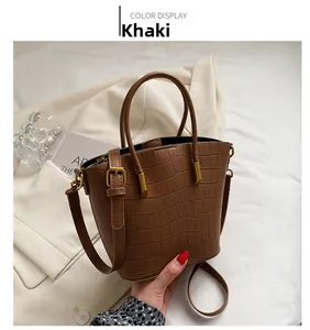 Detail of khaki crocodile pattern bucket bag showing gold hardware and texture