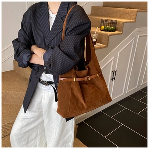 Détail d'un grand sac cabas vintage en daim marron avec boucle dorée porté par un modèle