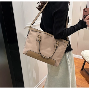 Detail of a large beige tote bag with brown handles and CLEAROK logo in a casual setting