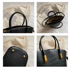Detail of black crocodile texture bag featuring gold hardware and protective base feet