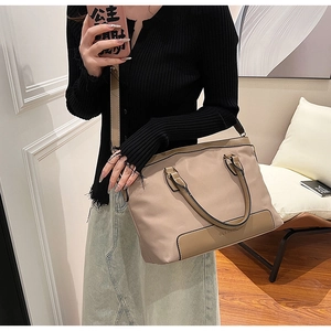 Detailed view of khaki nylon tote bag with black handles and leather accents on a model