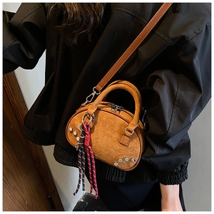 Détail du sac bandoulière en daim marron avec clous argentés et breloque tissée colorée