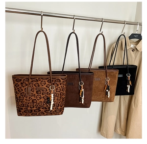 Various suede tote bags in leopard, brown, khaki, and black colors displayed on a rack