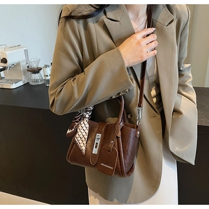 Détail du sac seau marron avec fermoir argenté et foulard en soie décoratif élégant