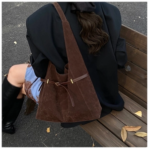 Détail du sac cabas vintage en daim marron avec lanières en cuir et boucles dorées