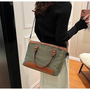 Detailed view of large olive green tote bag showing leather handles and premium stitching