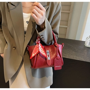 Détail du sac seau rouge avec décoration de foulard et étiquette de mode en cuir