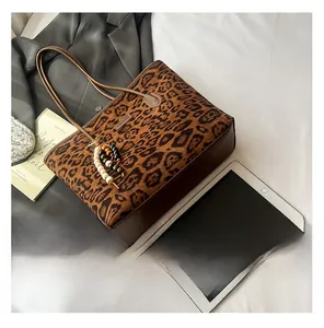 Detailed close-up of leopard print tote bag with beaded charm and leather trim details