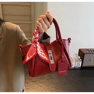 Détail du sac seau en cuir rouge avec fermoir argenté et foulard en soie décoratif