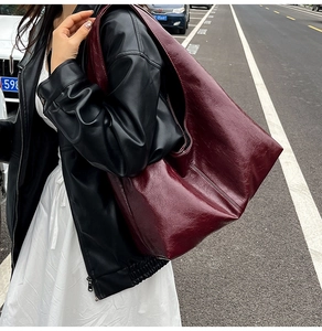 Dettaglio della grande borsa tote bordeaux in pelle cerata vintage indossata dal modello