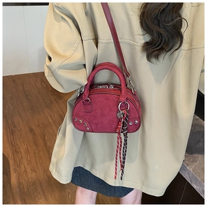 Détail du sac bowling en daim bordeaux avec rivets argentés et pendentif coeur chic