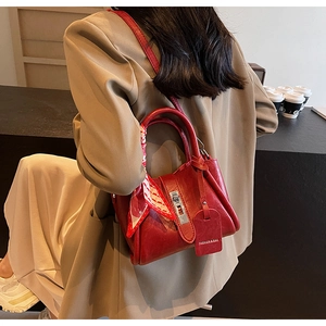 Detail of red leather bucket bag with silk scarf accent and golden hardware