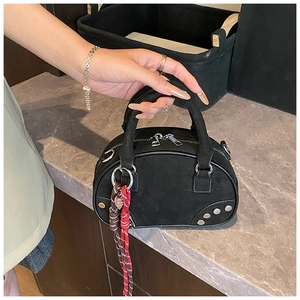 Détail d'un sac bowling noir en daim avec des rivets et un ornement en corde tressée