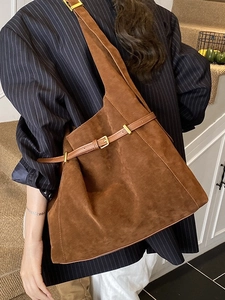 Sac cabas rétro en daim marron avec boucle décorative porté par un mannequin élégant