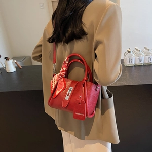 Détail du sac seau rouge texturé avec foulard en soie et boucle métallique argentée