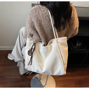Detail of soft white leather tote bag with brown knot charm and long shoulder straps