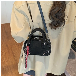 Détail du mini sac bowling en daim noir avec clous argentés et pompon tissé coloré