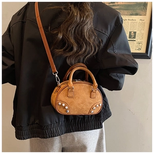 Détail du sac bowling en daim marron avec rivets métalliques et bandoulière amovible