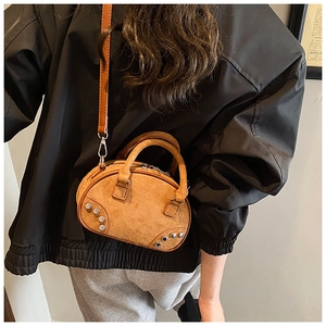 Détail du mini sac bowling en daim marron avec rivets argentés et bandoulière réglable