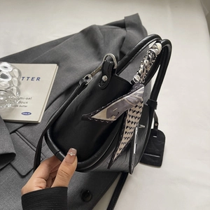 Sac seau élégant en cuir noir avec poignée en foulard de soie sur un blazer gris