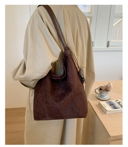 Detail of large brown suede shoulder bag showing soft texture and natural drape on shoulder