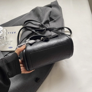 Sac seau noir élégant à texture litchi avec foulard floral sur fond gris haut de gamme