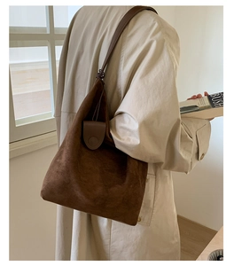Detail showing the matte suede texture and slim shoulder strap of this brown tote bag