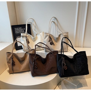 Row of five soft suede tote bags in various neutral colors with woven knot pendants