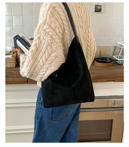 Detail of minimalist black hobo bag with matte suede texture and metallic ring connector